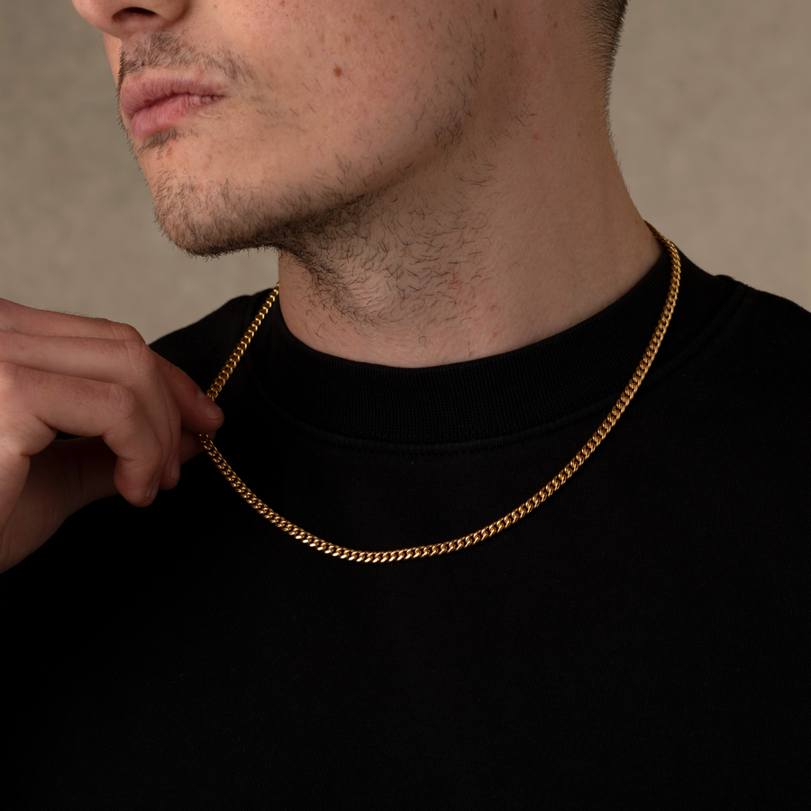 Man wearing a gold chain necklace against a neutral background