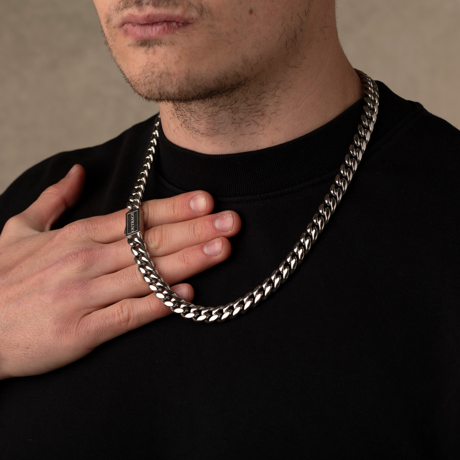 Man wearing a silver chain necklace against a neutral background