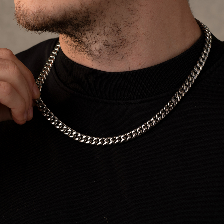 Man wearing a silver chain necklace against a neutral background