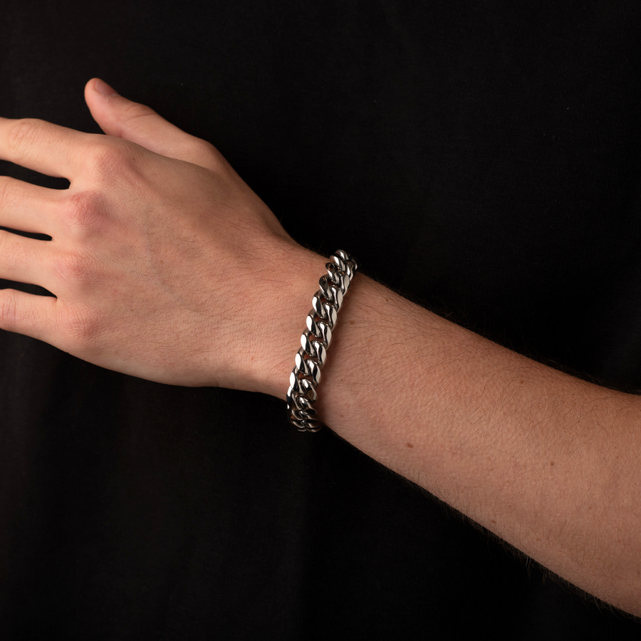 Hand wearing a silver chain bracelet on a black background