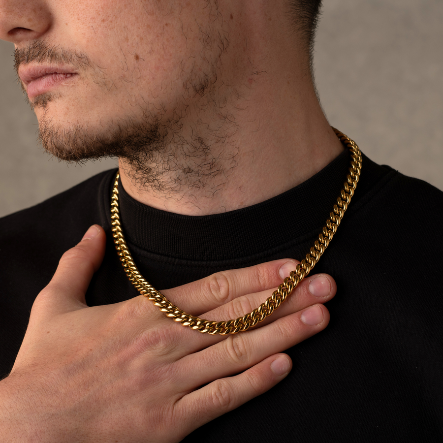 Man wearing a gold chain necklace with a neutral background