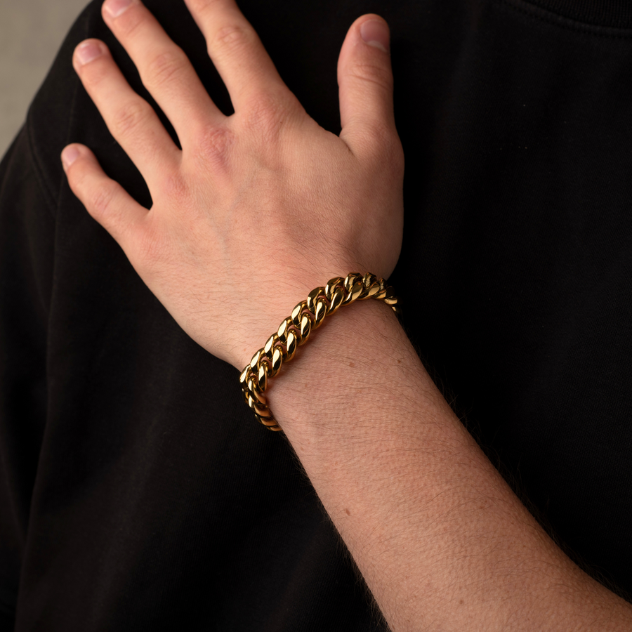 Gold chain bracelet on a person's wrist against a black background
