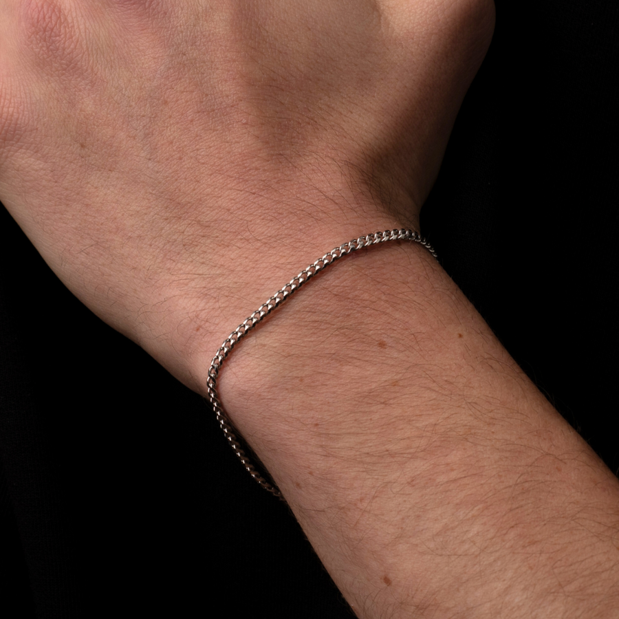 Silver bracelet on a person's wrist against a black background