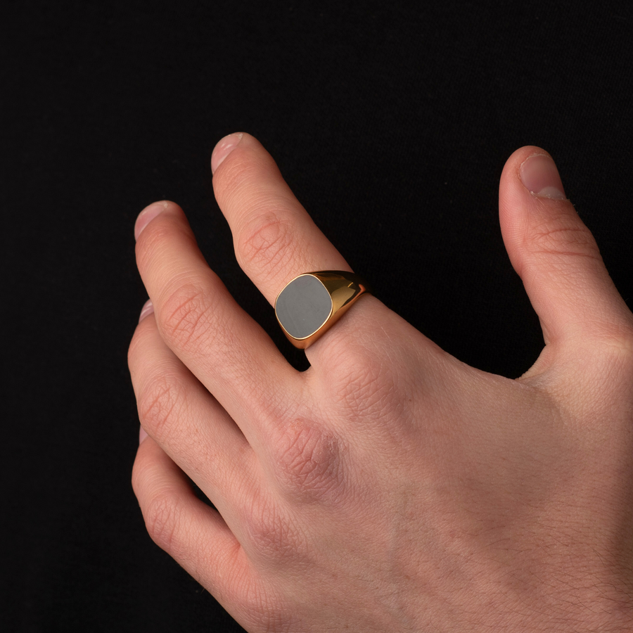 Hand wearing a gold ring with a dark background