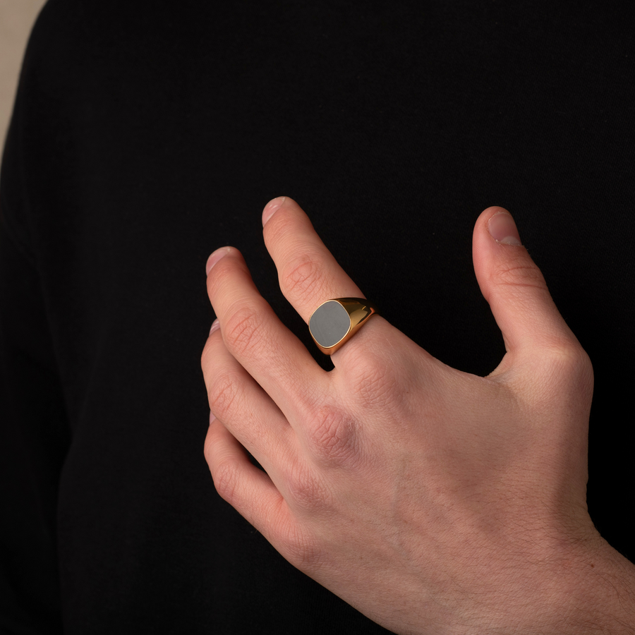 Hand wearing a gold ring with a dark background
