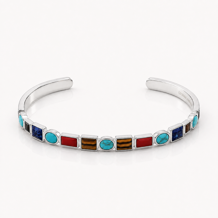 A sterling silver cuff bracelet featuring a row of colorful inlay stones, including turquoise, red, brown, and blue, set against a clean white background.