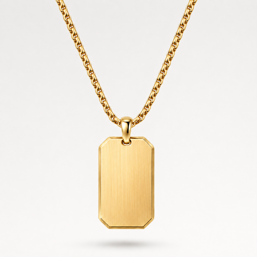 A gold dog tag pendant necklace with a brushed finish and a matching gold chain, shown against a clean white background.