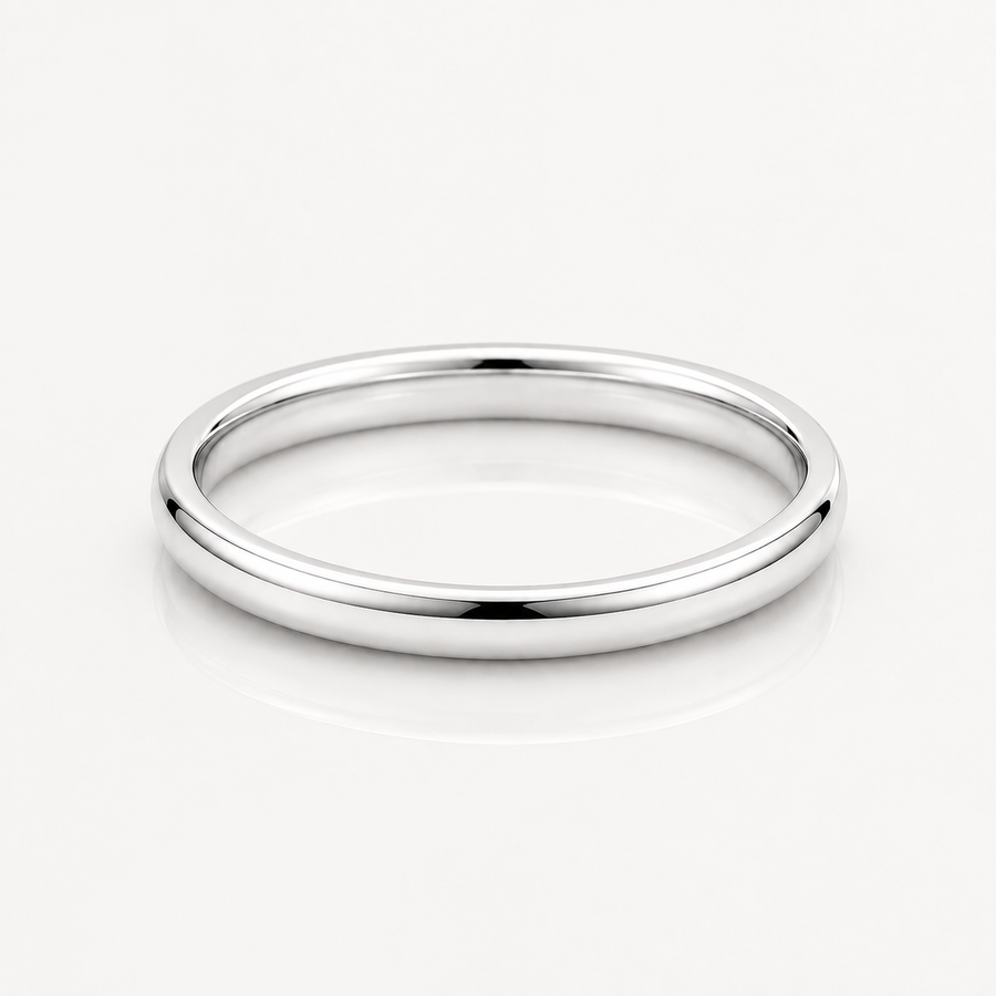 A minimalist, polished silver band ring with a smooth, rounded profile, displayed on a clean white reflective surface.