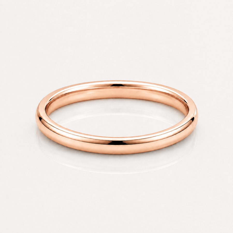 A minimalist rose gold band ring with a smooth, polished finish, shown on a clean white reflective surface.