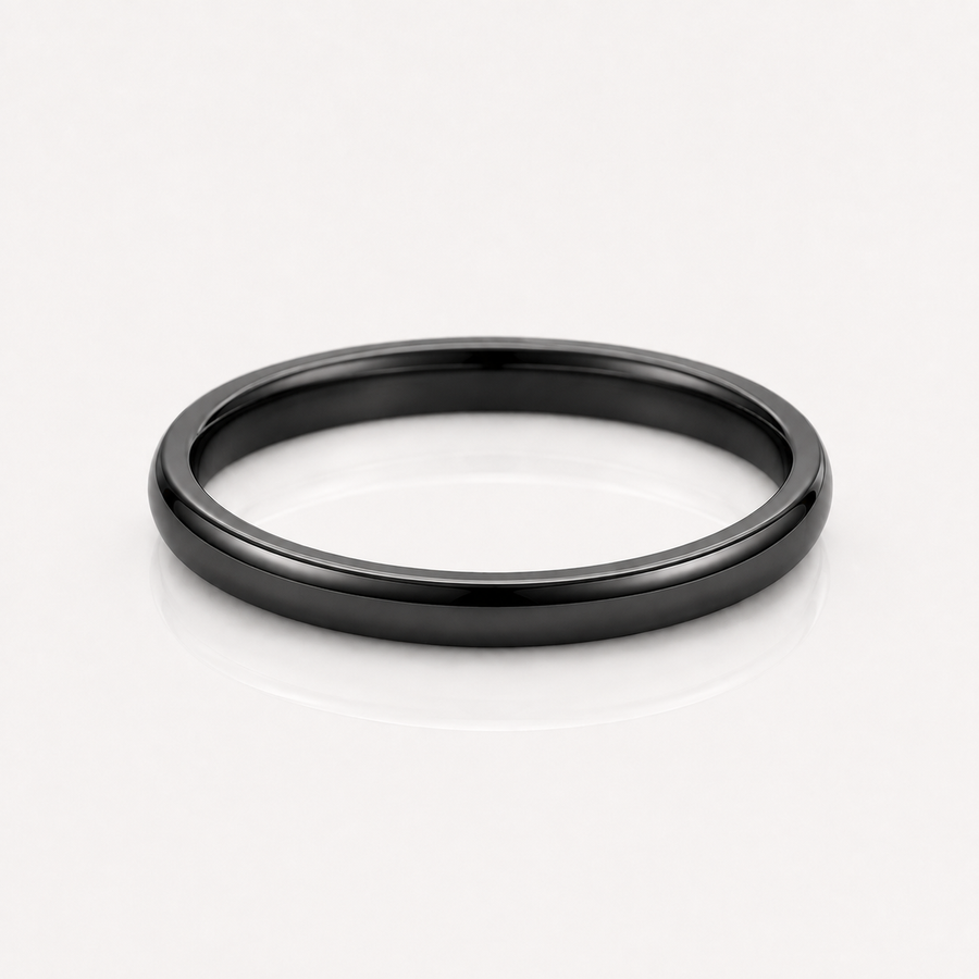 A minimalist matte black metal band ring, photographed from a top-down perspective on a clean white reflective surface.