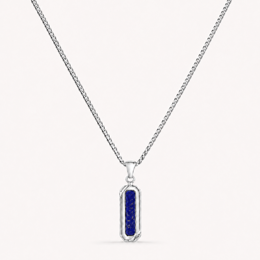 A silver-toned chain necklace with a vertical rectangular pendant featuring a deep blue textured center, shown on a light off-white background.