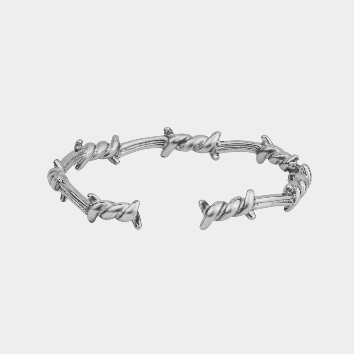 Silver barbed wire bracelet on a light gray background