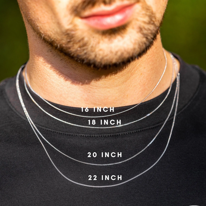 Man wearing necklaces of different lengths with labeled measurements on a black shirt.