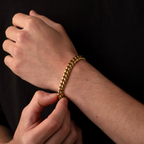 Gold chain bracelet being worn on a wrist against a black background