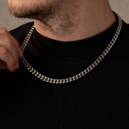 Man wearing a silver chain necklace against a neutral background