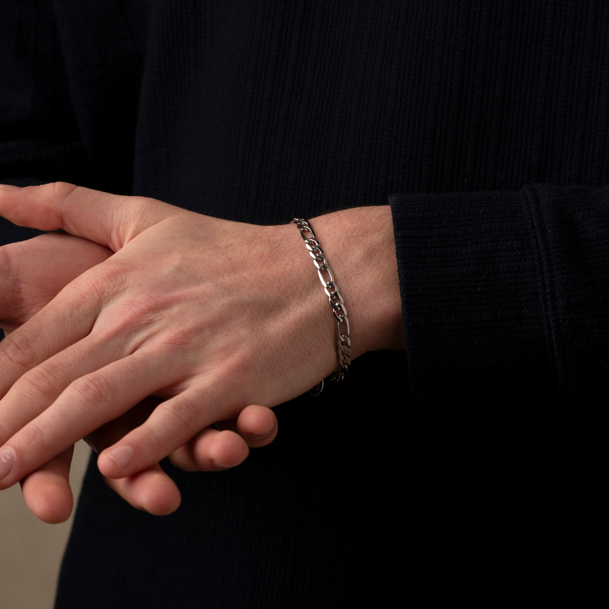 Hand wearing a bracelet with a black background