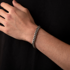 Hand wearing a silver chain bracelet on a black background