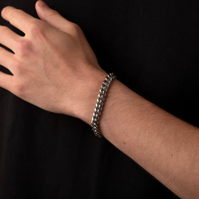 Hand wearing a silver chain bracelet on a black background