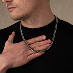 Man wearing a silver chain necklace with a neutral background