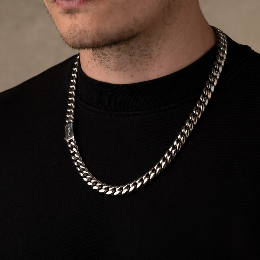 Silver chain necklace worn by a person on a plain background