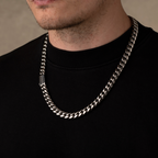 Silver chain necklace worn by a person on a plain background