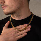Man wearing a gold chain necklace with a neutral background