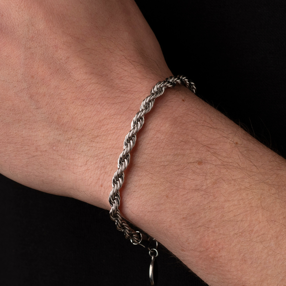 Hand wearing a silver bracelet on a black background