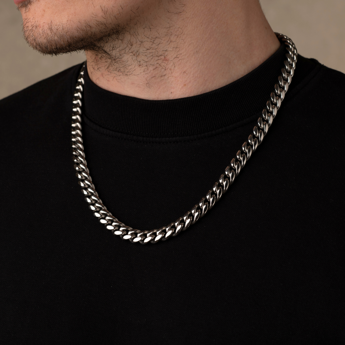 Silver chain necklace worn by a person on a plain background