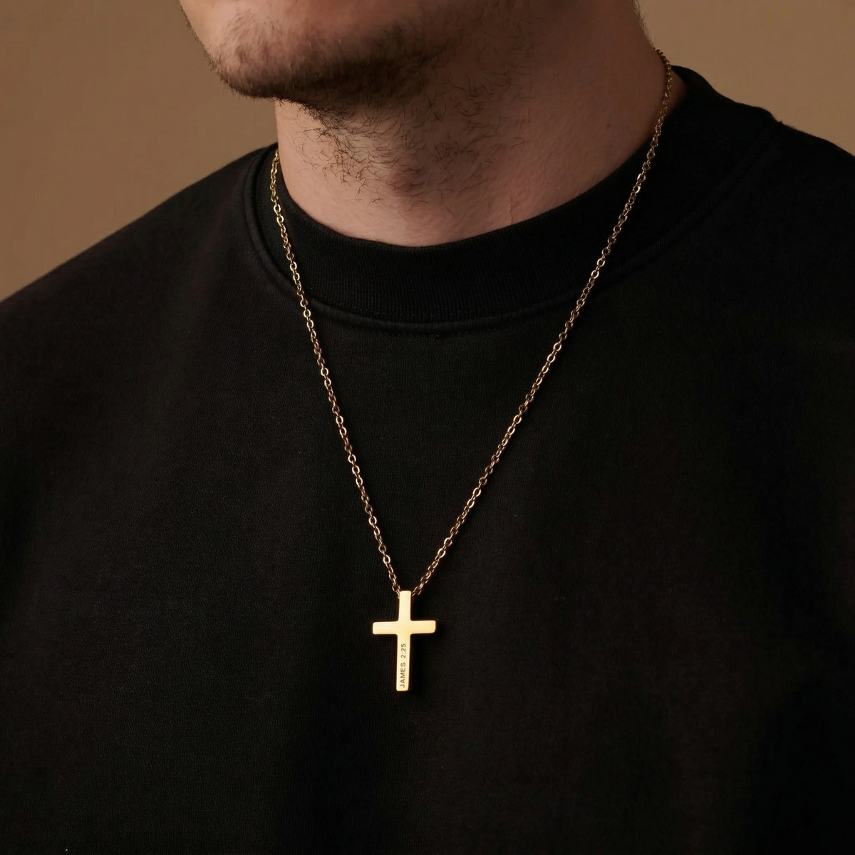 Gold cross necklace on a person wearing a black shirt against a brown background