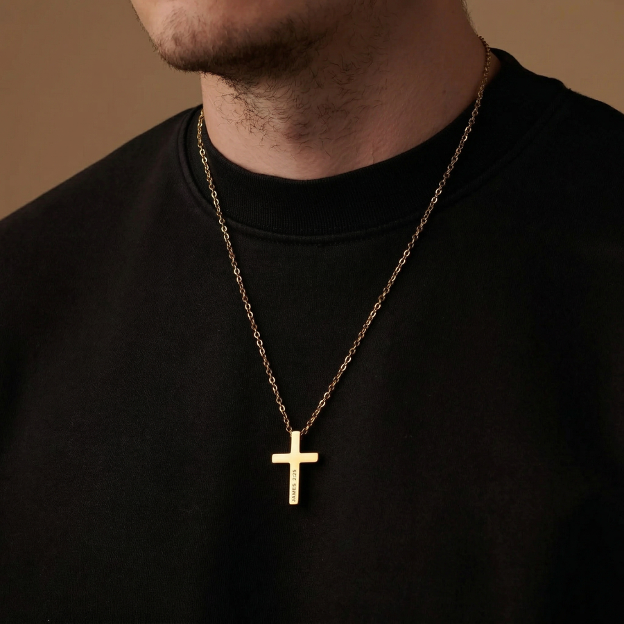 Gold cross necklace on a person wearing a black shirt against a brown background