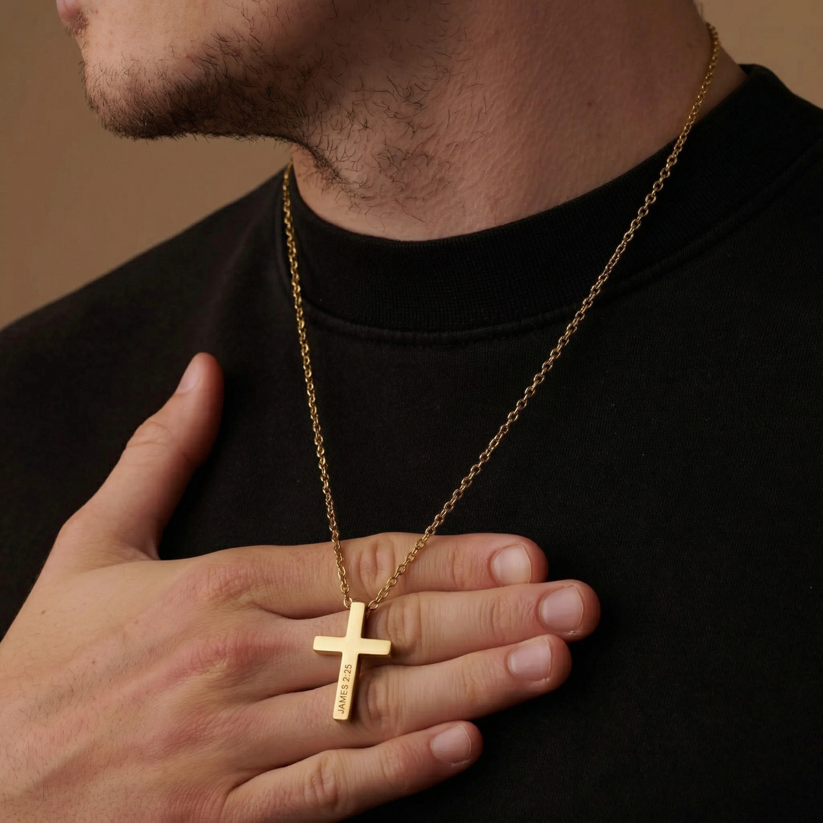 Man wearing a gold necklace with a cross pendant, holding it close to his chest.