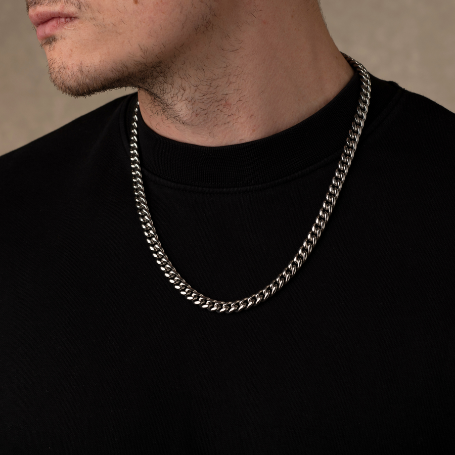 Man wearing a silver chain necklace against a neutral background