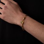 Gold bracelet on a wrist against a black background