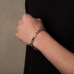 Person wearing a silver chain bracelet on a neutral background
