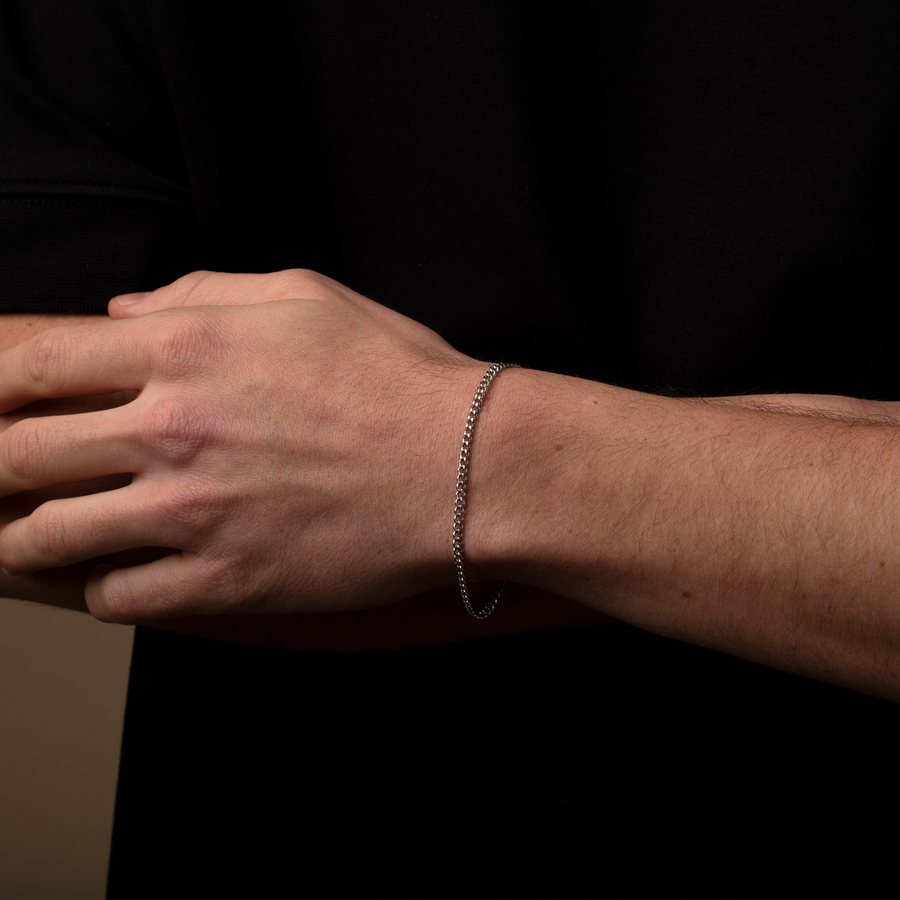 Hand wearing a silver bracelet against a black background