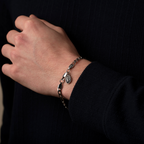 Hand wearing a silver bracelet with a dark background