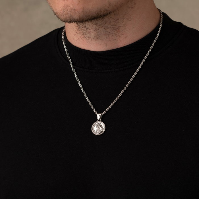 Silver necklace with a pendant worn by a person against a neutral background