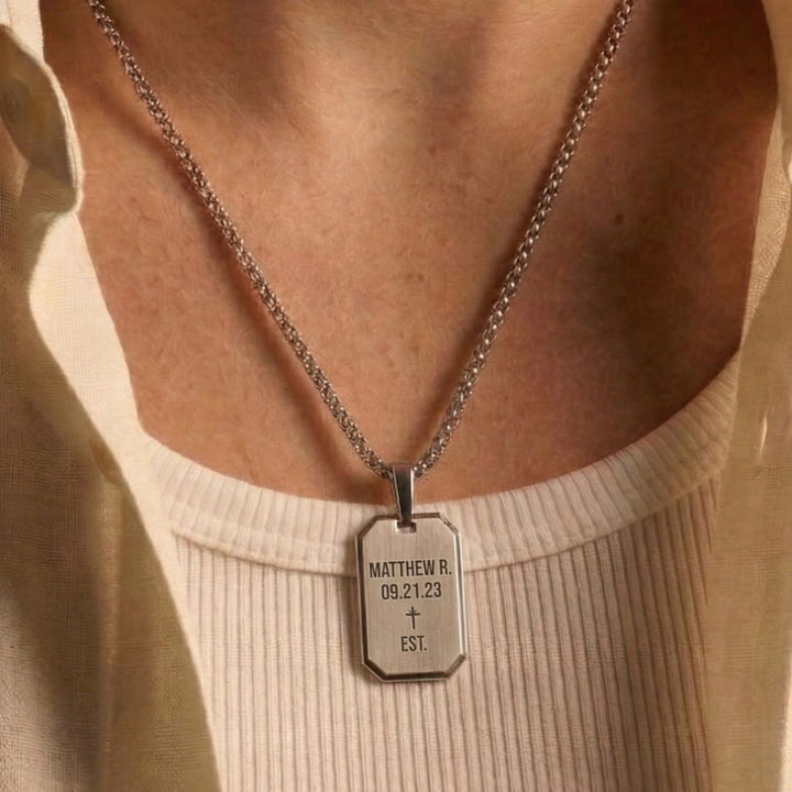 A silver necklace with a rectangular pendant that displays the name Matthew R. and the date 09.21.23 EST.