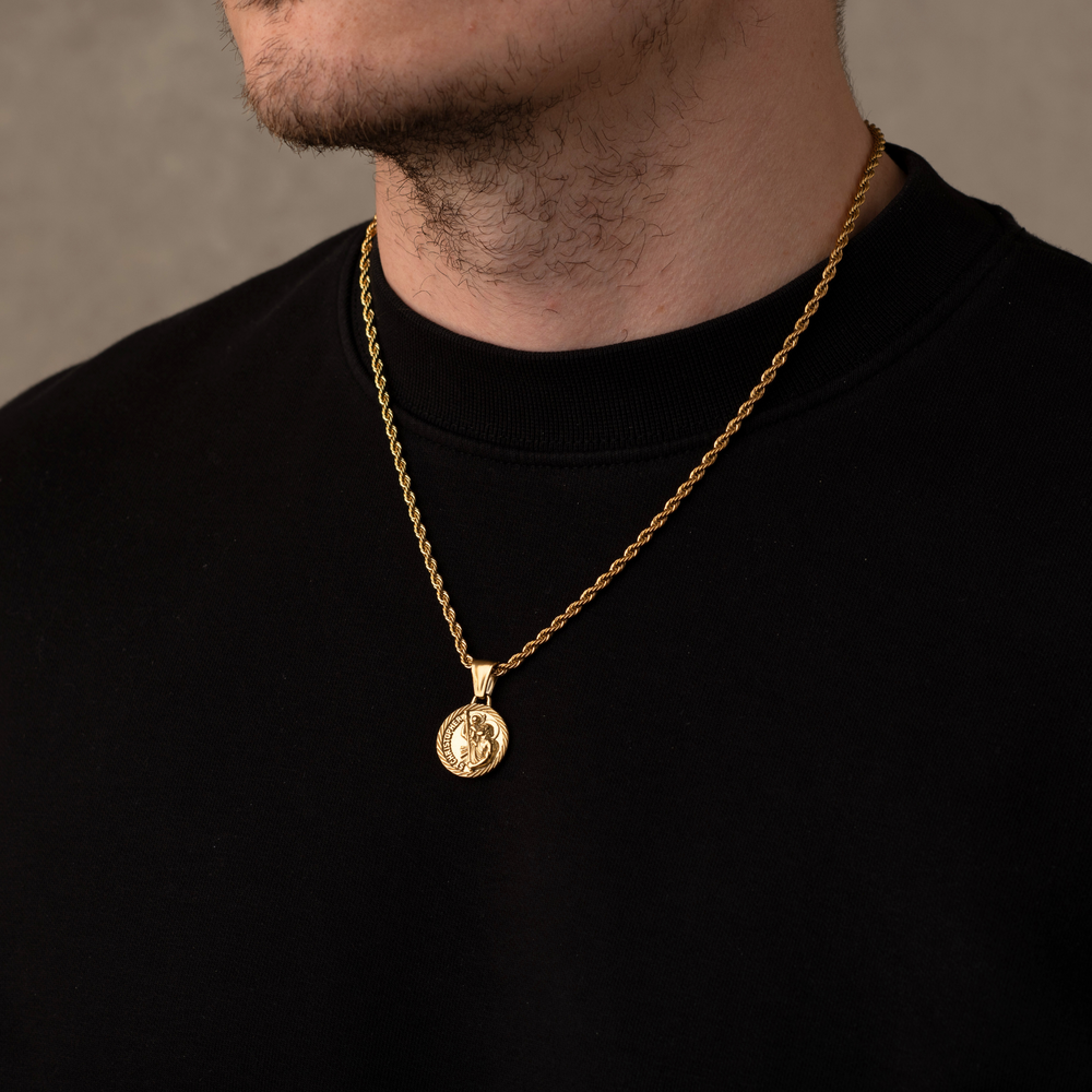 Gold necklace with a pendant worn by a person against a neutral background