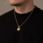 Gold necklace with a pendant worn by a person against a neutral background