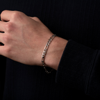 Hand wearing a silver chain bracelet against a black background