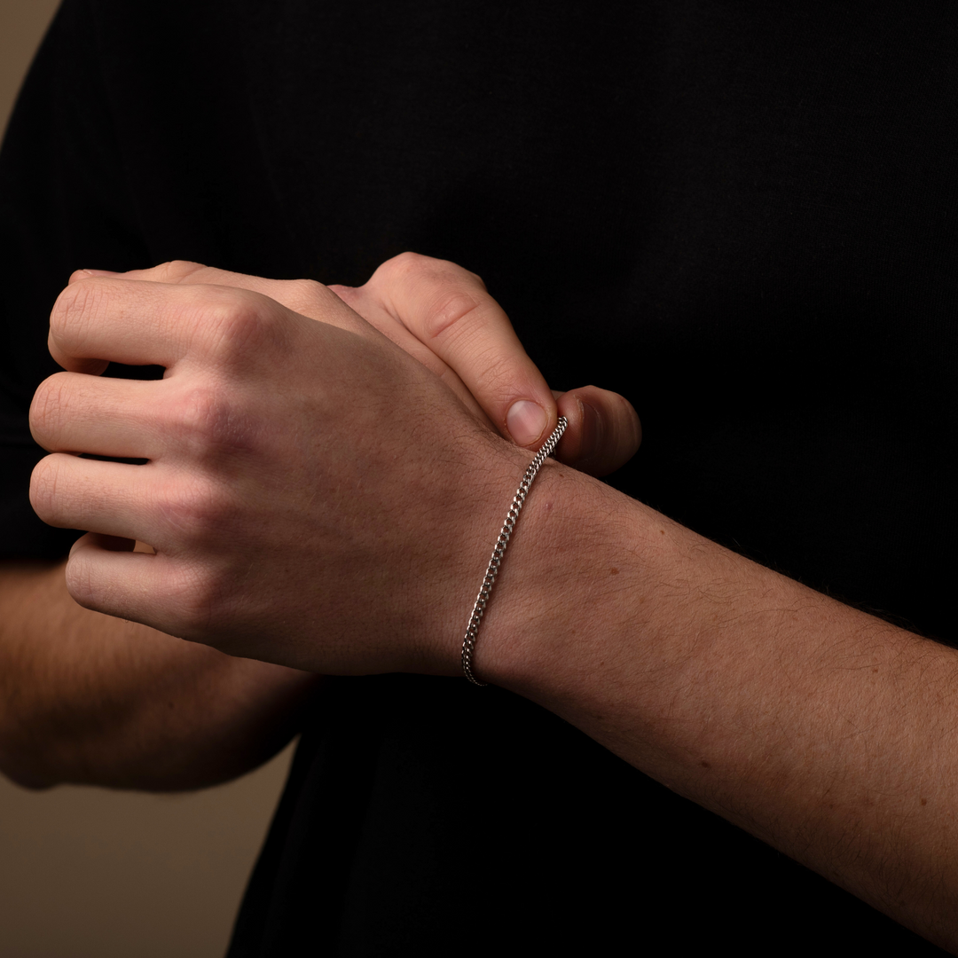 Close-up of a person's wrist with a silver bracelet against a dark background