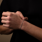 Close-up of a person's wrist with a silver bracelet against a dark background