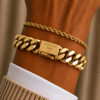 A close-up of a person's wrist wearing two gold bracelets: a thick curb-link chain bracelet engraved with 'I LOVE YOU Lady' and a thinner rope-style chain bracelet, layered over a white collared shirt and beige knit sweater cuff.