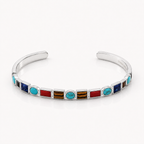 A sterling silver cuff bracelet featuring a row of colorful inlay stones, including turquoise, red, brown, and blue, set against a clean white background.