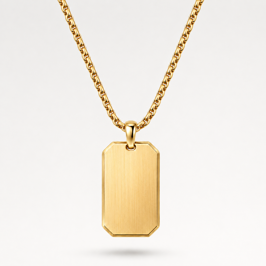 A gold dog tag pendant necklace with a brushed finish and a matching gold chain, shown against a clean white background.