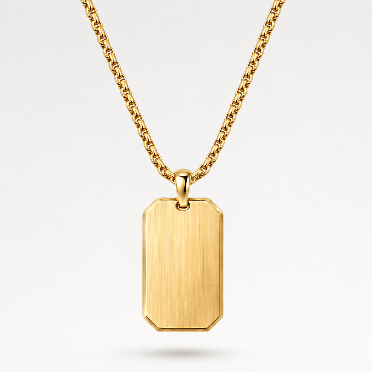 A gold dog tag pendant necklace with a brushed finish and a matching gold chain, shown against a clean white background.