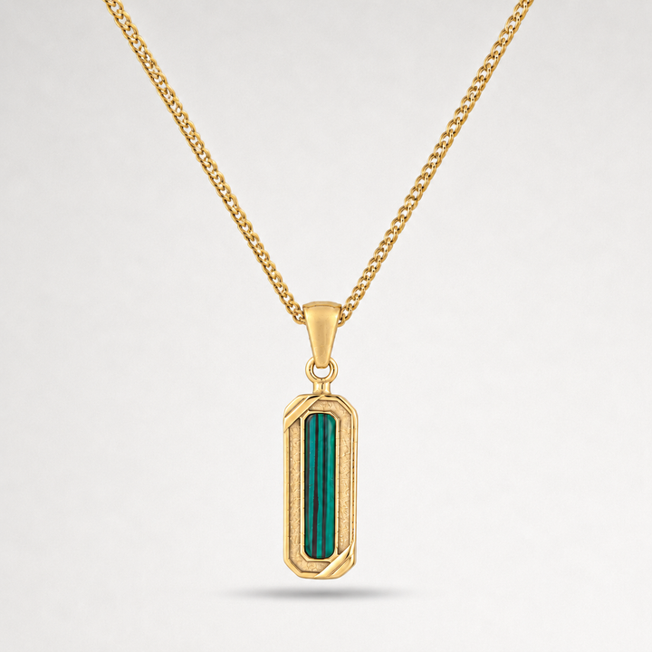 Gold pendant with green stone on a white background