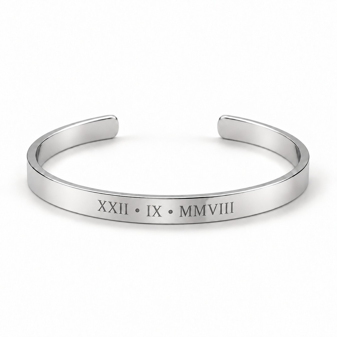 A polished silver cuff bracelet with Roman numerals engraved on the front, displayed on a clean white background.