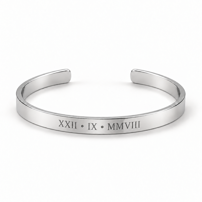 A polished silver cuff bracelet with Roman numerals engraved on the front, displayed on a clean white background.